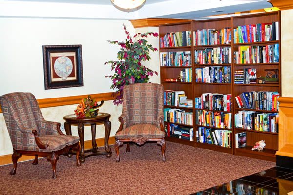 A cozy reading corner with a bookshelf, chairs, and a small table.
