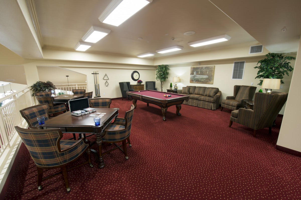 A cozy basement game room with a pool table and seating area.