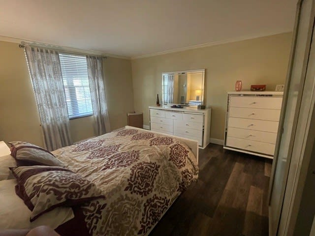 A cozy bedroom with a bed, dresser, mirror, and window with curtains.