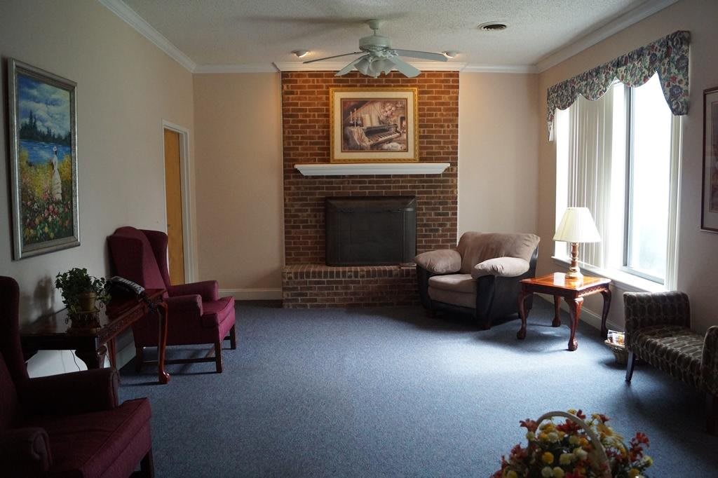 A cozy living room with a brick fireplace, armchairs, and a sofa alongside a coffee table.
