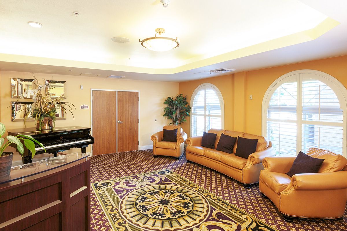 A cozy living room with leather seating, a patterned carpet, and large windows letting in natural light.