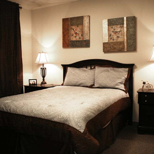 A cozy bedroom with a neatly made bed, bedside tables, and decorative artwork on the walls.