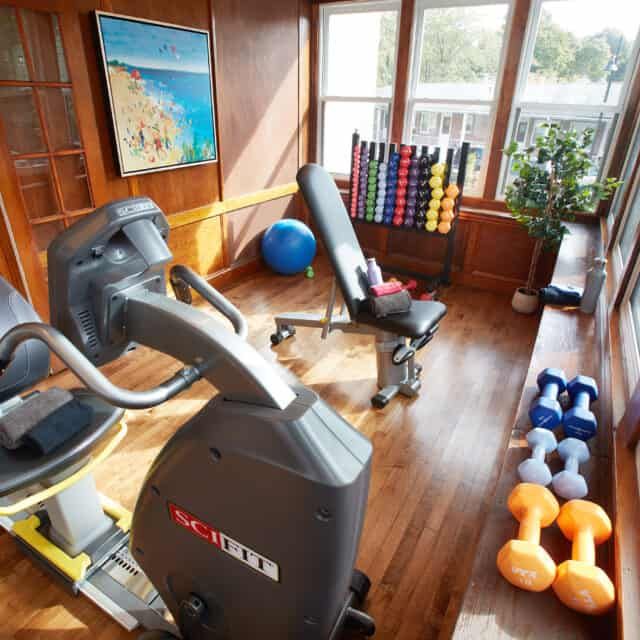 A well-lit home gym with various exercise equipment including a treadmill and dumbbells.