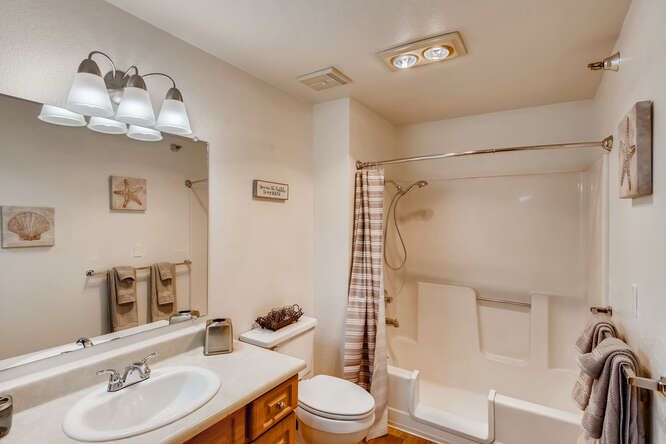 A well-lit bathroom with a sink, toilet, and shower area.