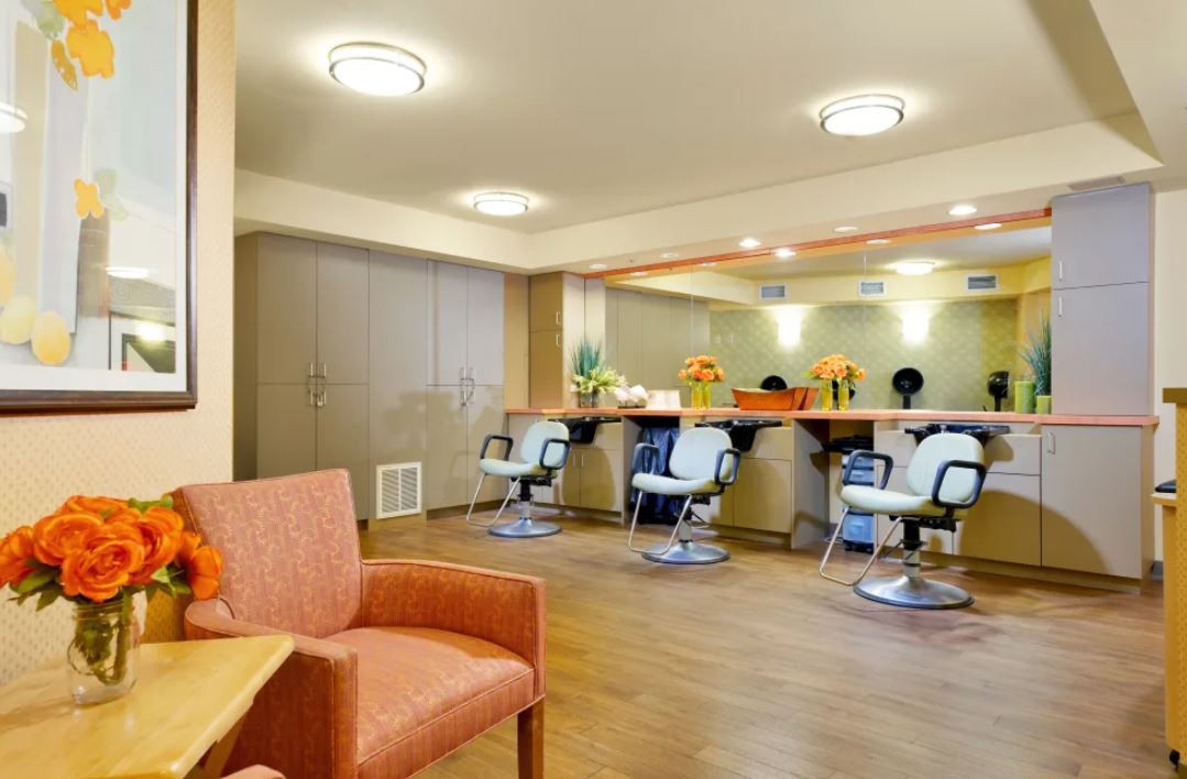 A modern hair salon interior featuring styling chairs, large mirrors, and a comfortable waiting area.