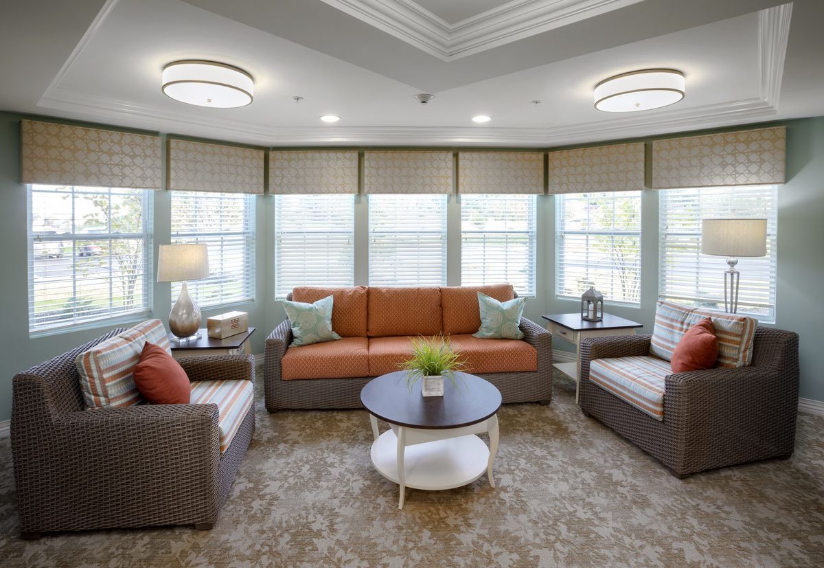 A cozy and modern living room with a sofa, armchairs, and a coffee table surrounded by large windows.