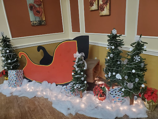 A festive display featuring a colorful Santa sleigh surrounded by decorated Christmas trees and winter decor.