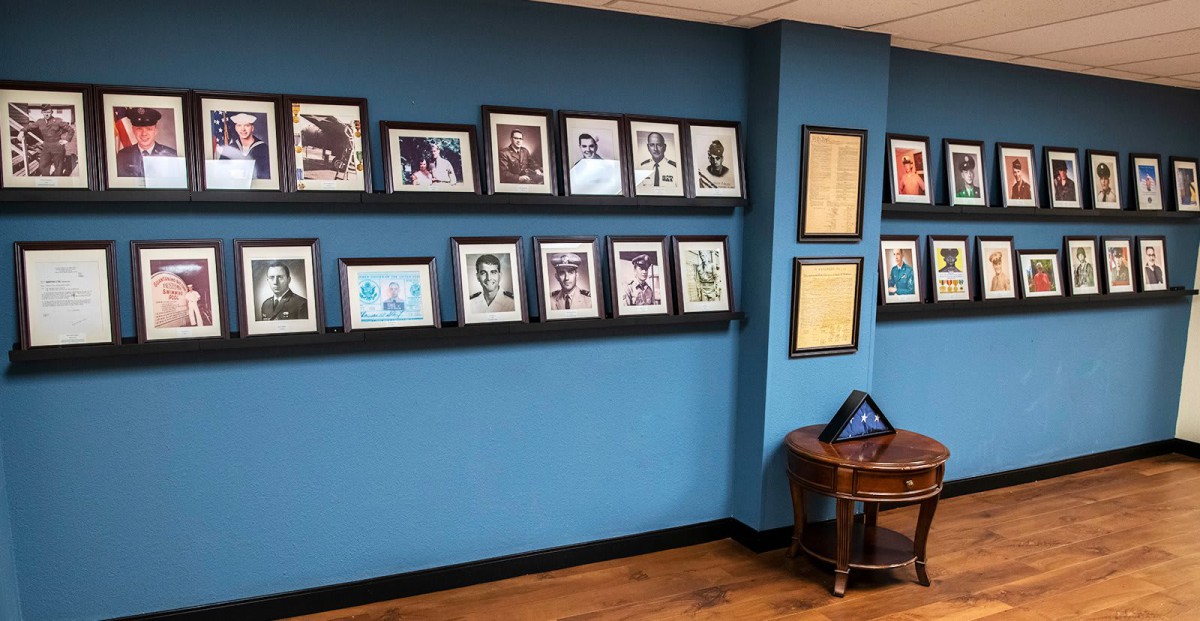 A gallery wall displaying a series of framed photographs and art on a blue painted surface.