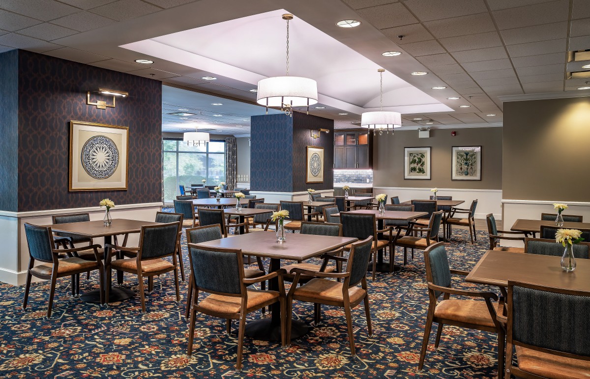 A spacious and well-decorated dining area with tables and chairs arranged neatly under modern lighting fixtures.