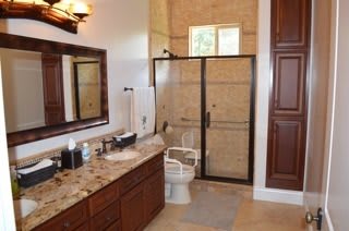 A well-appointed bathroom with a glass-enclosed shower, granite countertops, and wooden cabinetry.