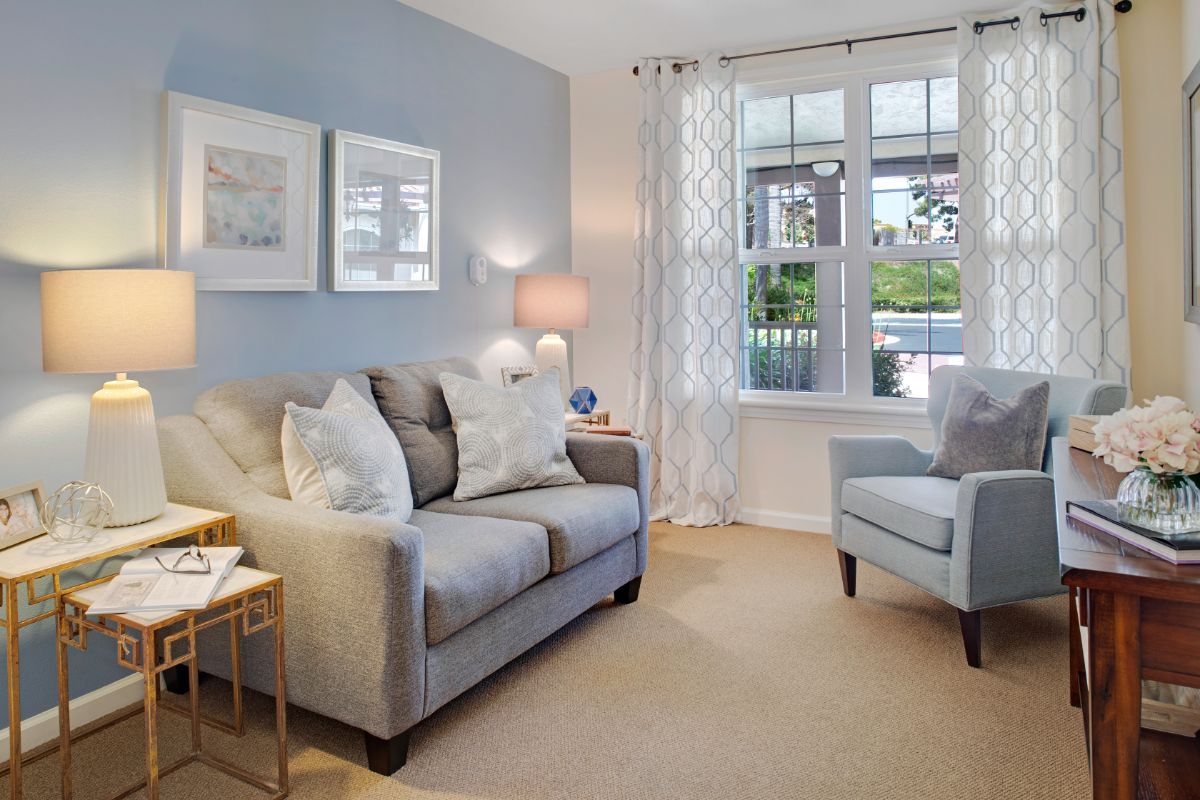 A cozy and contemporary living room featuring a comfortable sofa, armchair, large window, and wall artwork.