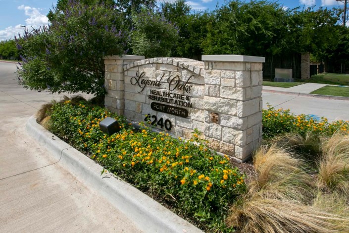 Entrance sign for a residential or commercial area with landscaping and flowers.