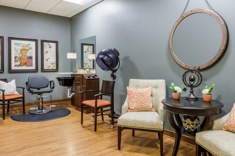 A cozy and well-decorated hair salon interior with seating and styling equipment.
