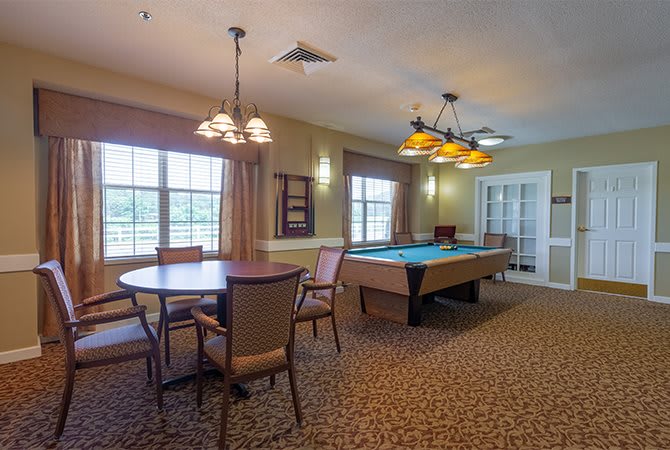 A cozy game room featuring a pool table and seating area with ample natural light.
