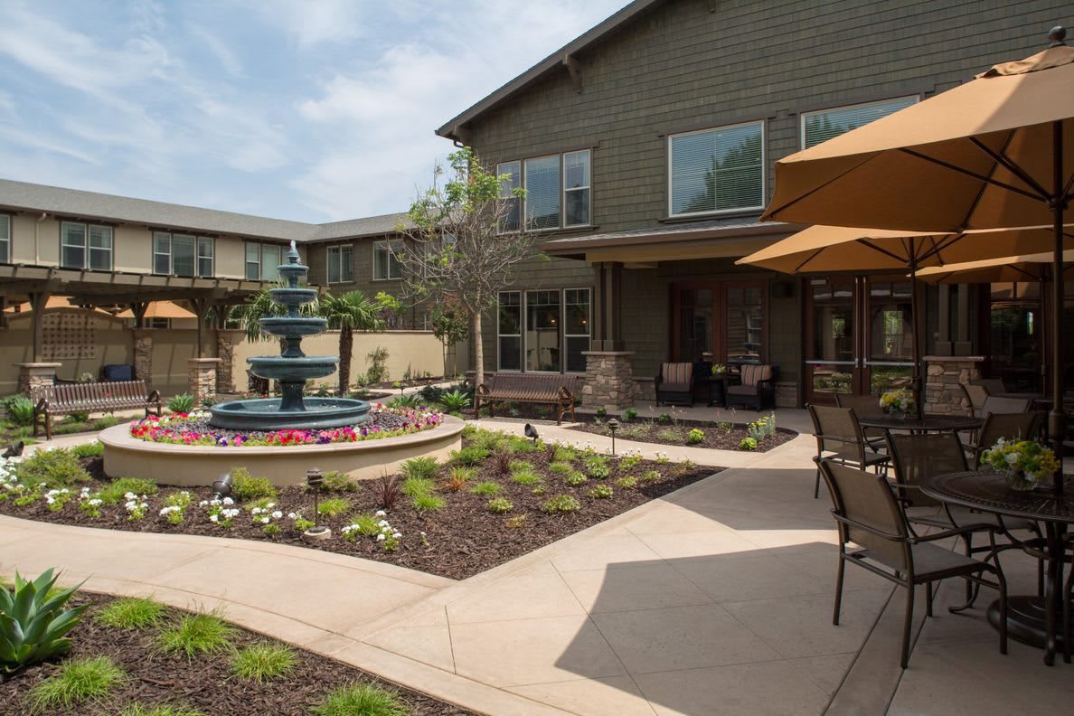 A courtyard with a fountain and outdoor seating surrounded by landscaped gardens.