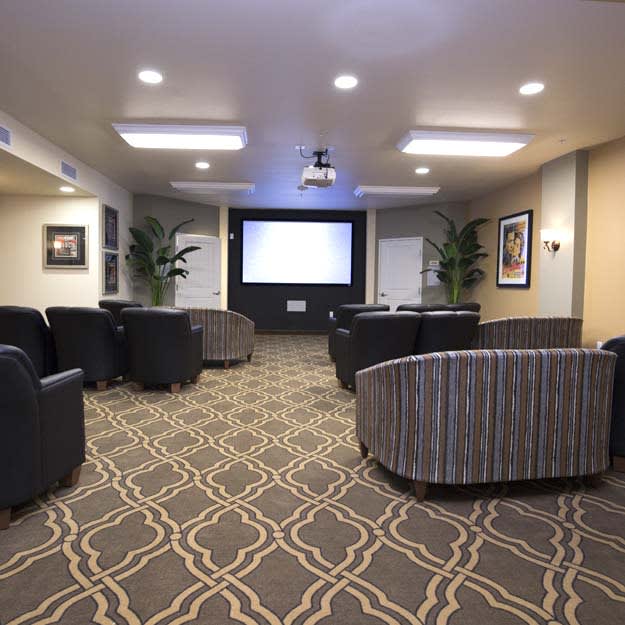A modern conference room featuring comfortable seating and a large projector screen.