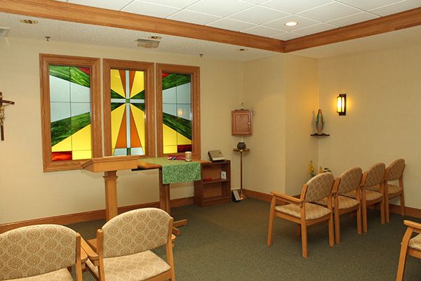 A small chapel with stained glass windows and simple seating arrangements.