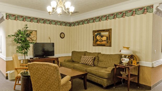 A traditionally decorated living room featuring a sofa, television, and chandelier.