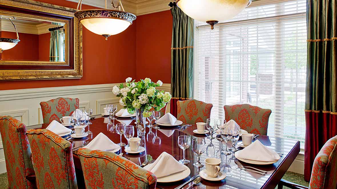 An elegantly set dining room with a floral centerpiece and a chandelier.