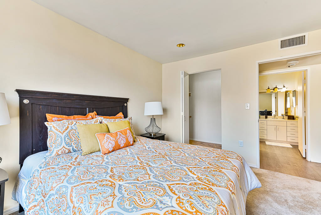 A cozy bedroom with a patterned bedspread and decorative pillows.