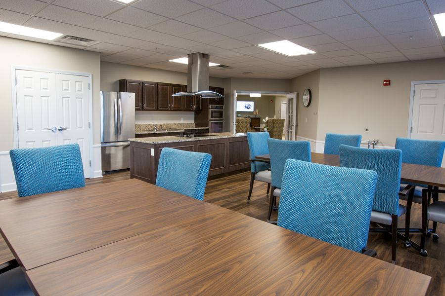 A modern kitchen and dining area with blue chairs and wooden tables.