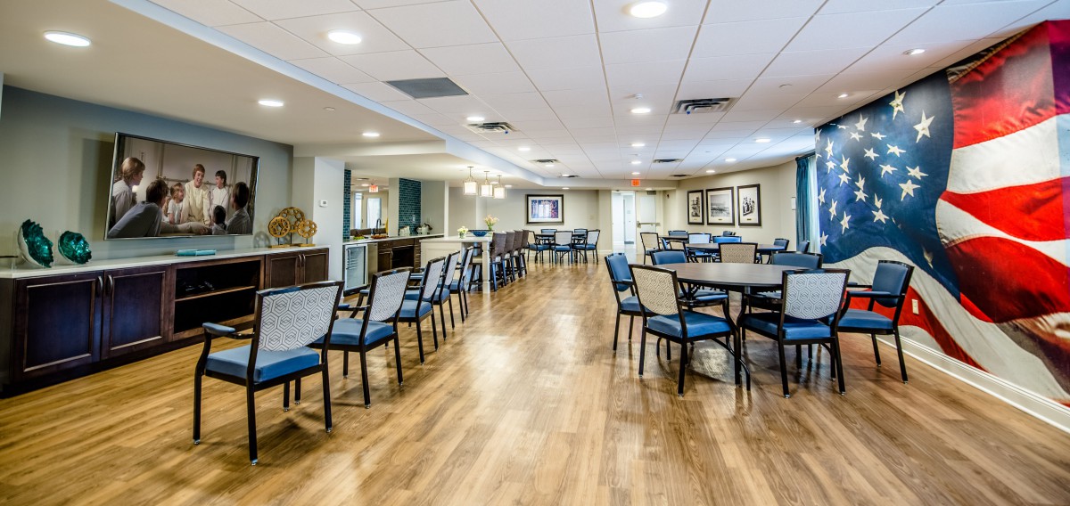 A spacious dining room featuring multiple tables and chairs on a hardwood floor, with bright lighting and modern interior design.