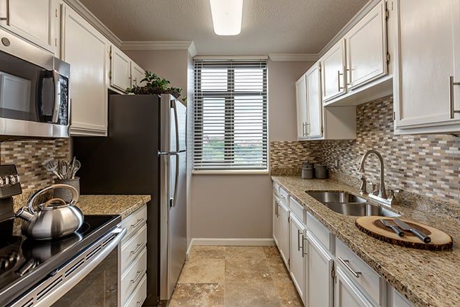 A modern kitchen with white cabinets and a stainless steel refrigerator.