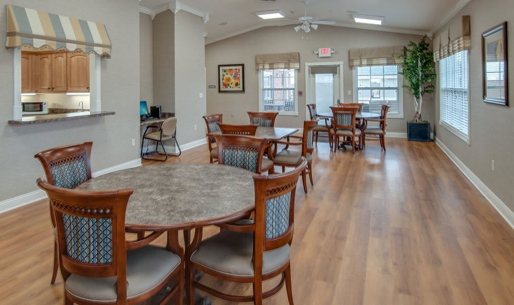 A spacious dining room with wooden tables and chairs, featuring wood flooring and large windows.