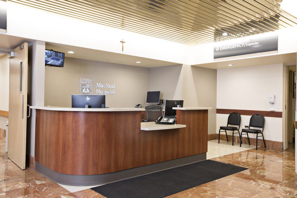 A modern reception area with a wooden desk and waiting chairs.