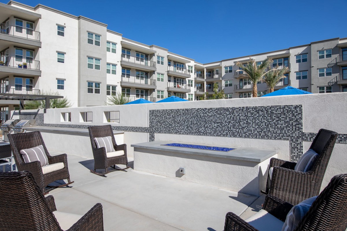 A modern apartment complex featuring an outdoor patio area with comfortable seating and a fire pit.