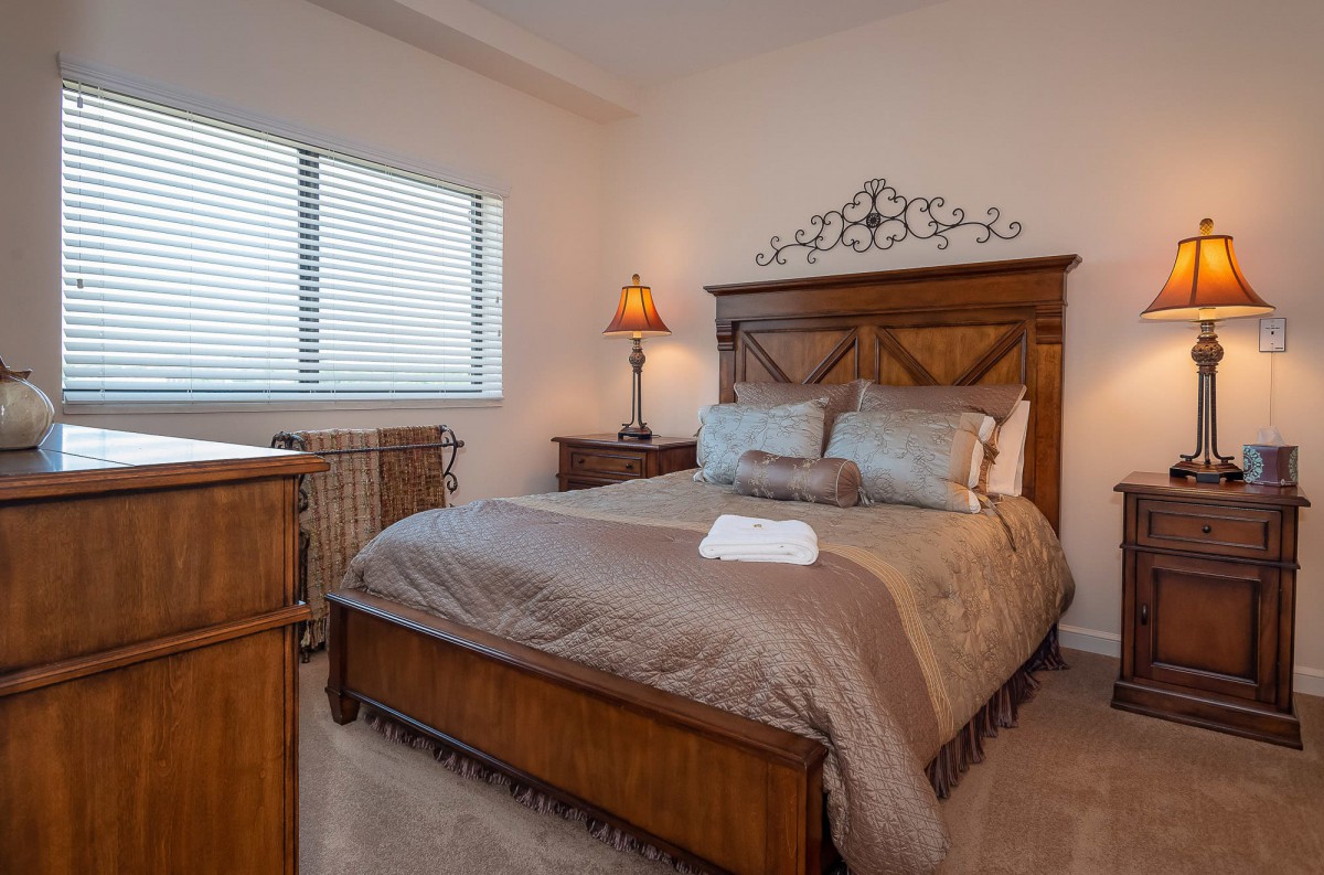 A cozy bedroom with a wooden bed frame and warm lighting.