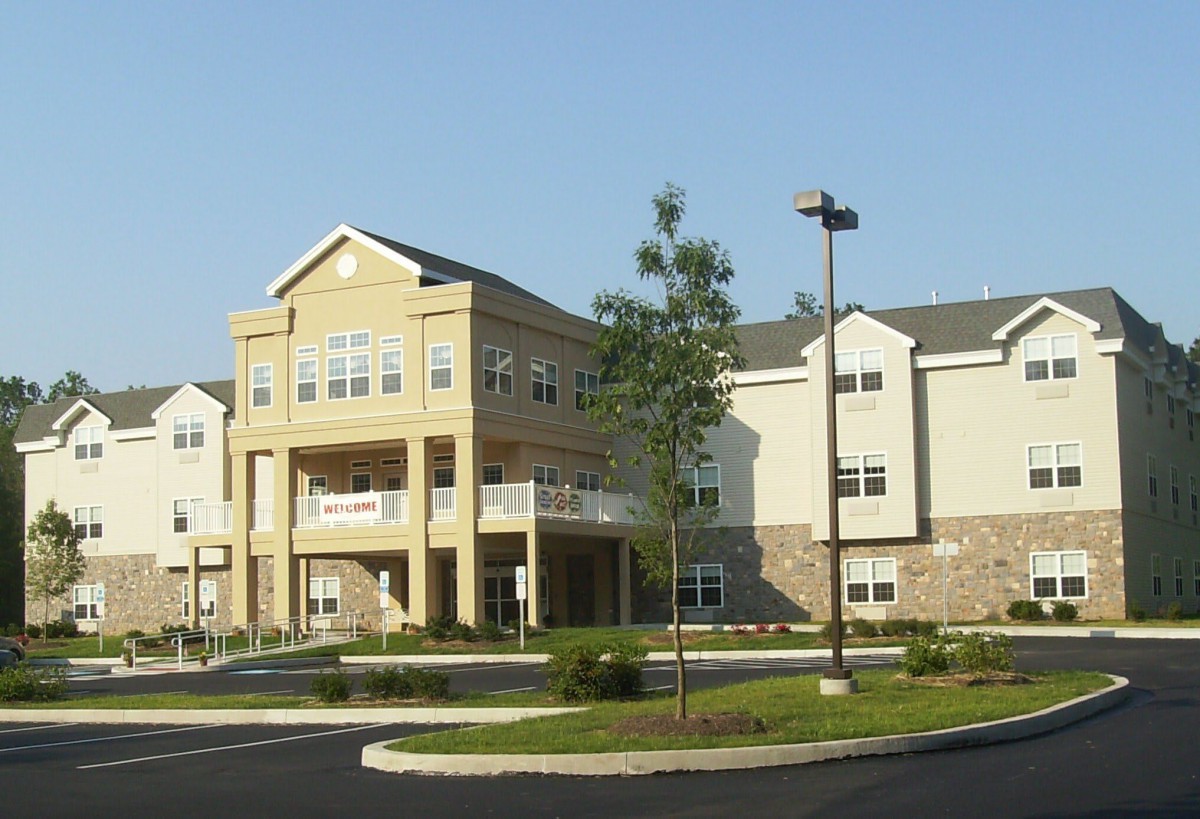 A modern residential building with balconies and a landscaped parking area.