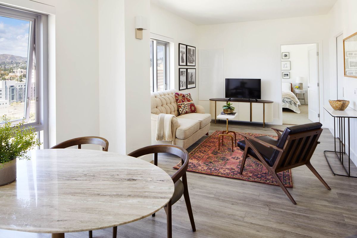 A modern living room with a cozy sofa, television, and dining area.