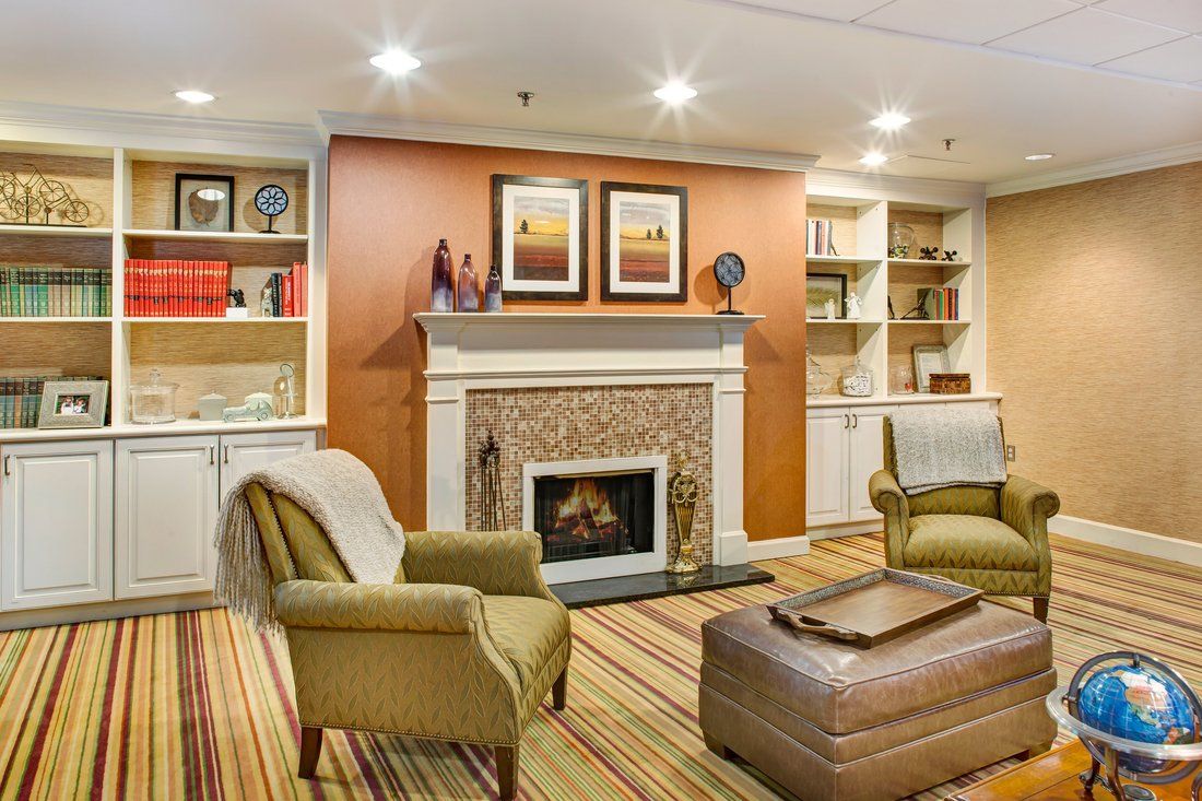 A cozy living room featuring a fireplace, armchairs, and elegant bookshelves with modern decor.