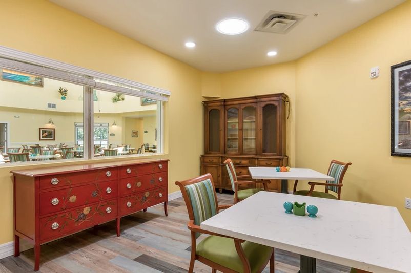 A cozy dining room with tables, chairs, and a wooden cabinet.