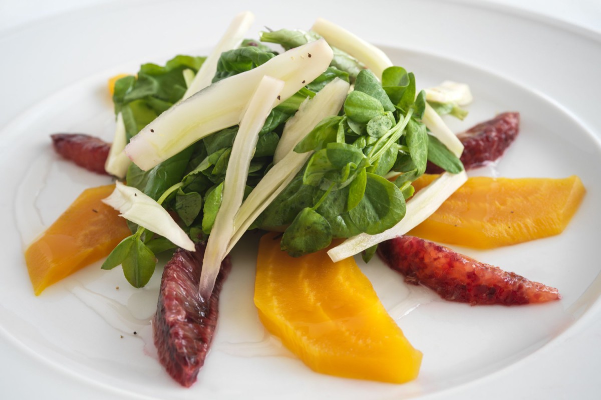 A gourmet salad featuring fresh greens, white asparagus, and colorful beets.