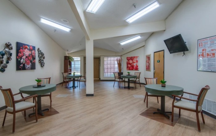 A spacious dining area with multiple tables and chairs, featuring decorative art on the walls.
