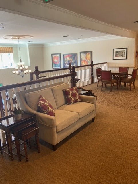 A cozy living area with a sofa, railing, and artwork on the walls.