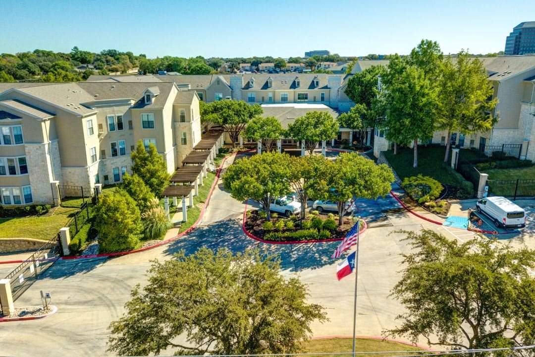 Aerial view of a landscaped building complex with a central driveway and flags.