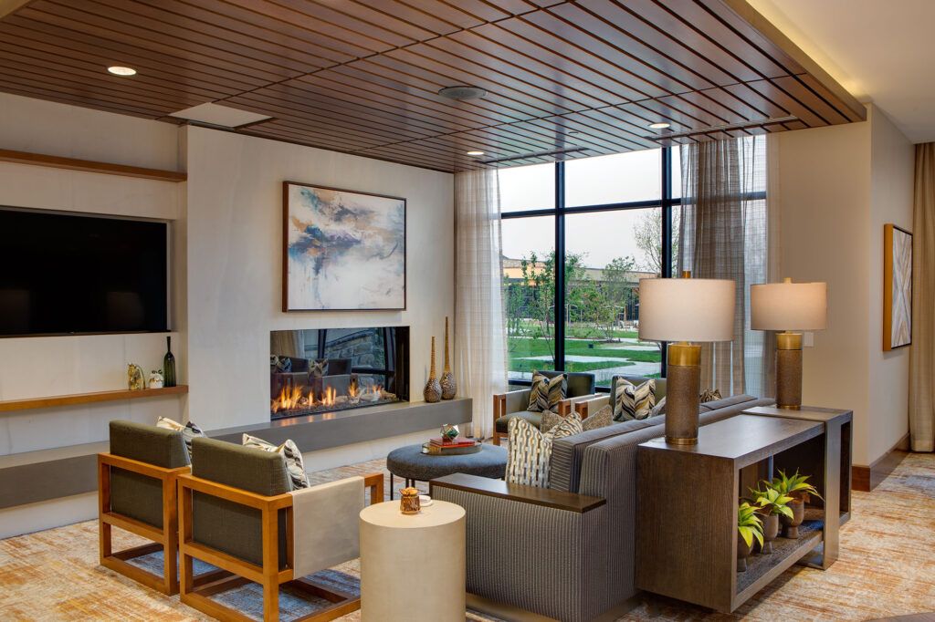 A modern living room featuring a cozy fireplace, contemporary furniture, and large windows overlooking the outdoors.