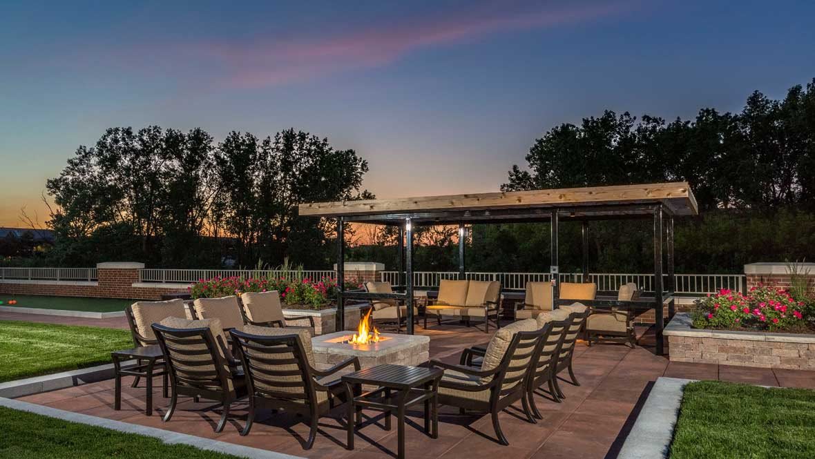 A cozy outdoor patio with seating around a fire pit during sunset.