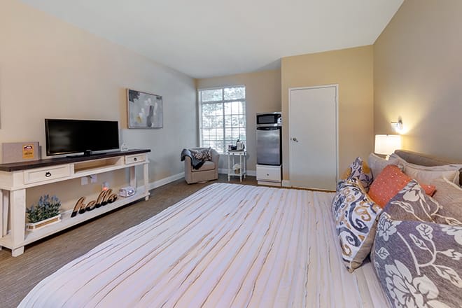 A modern bedroom featuring a cozy bed, stylish furniture, and a large window allowing natural light.