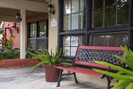 A cozy porch with a red bench and potted plants.