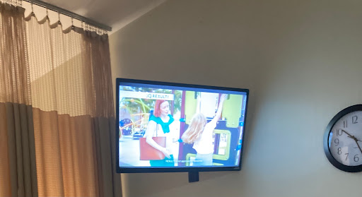 A television mounted on the wall displaying a colorful scene.