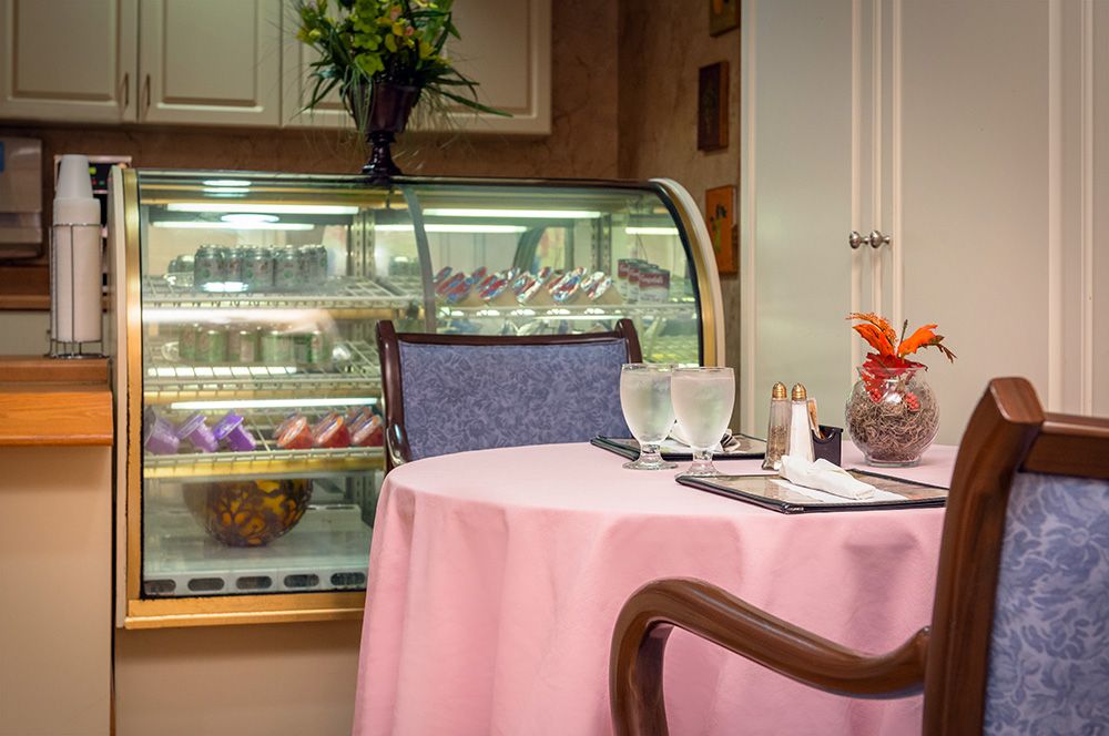 A cozy cafe setting with a pink tablecloth table and a dessert display in the background.