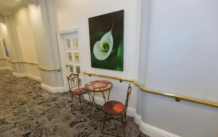 A cozy hallway corner with a small table, two chairs, and artwork on the wall.