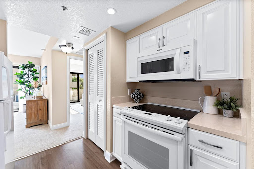 A modern kitchen featuring white cabinetry, a microwave, and a sleek stove.