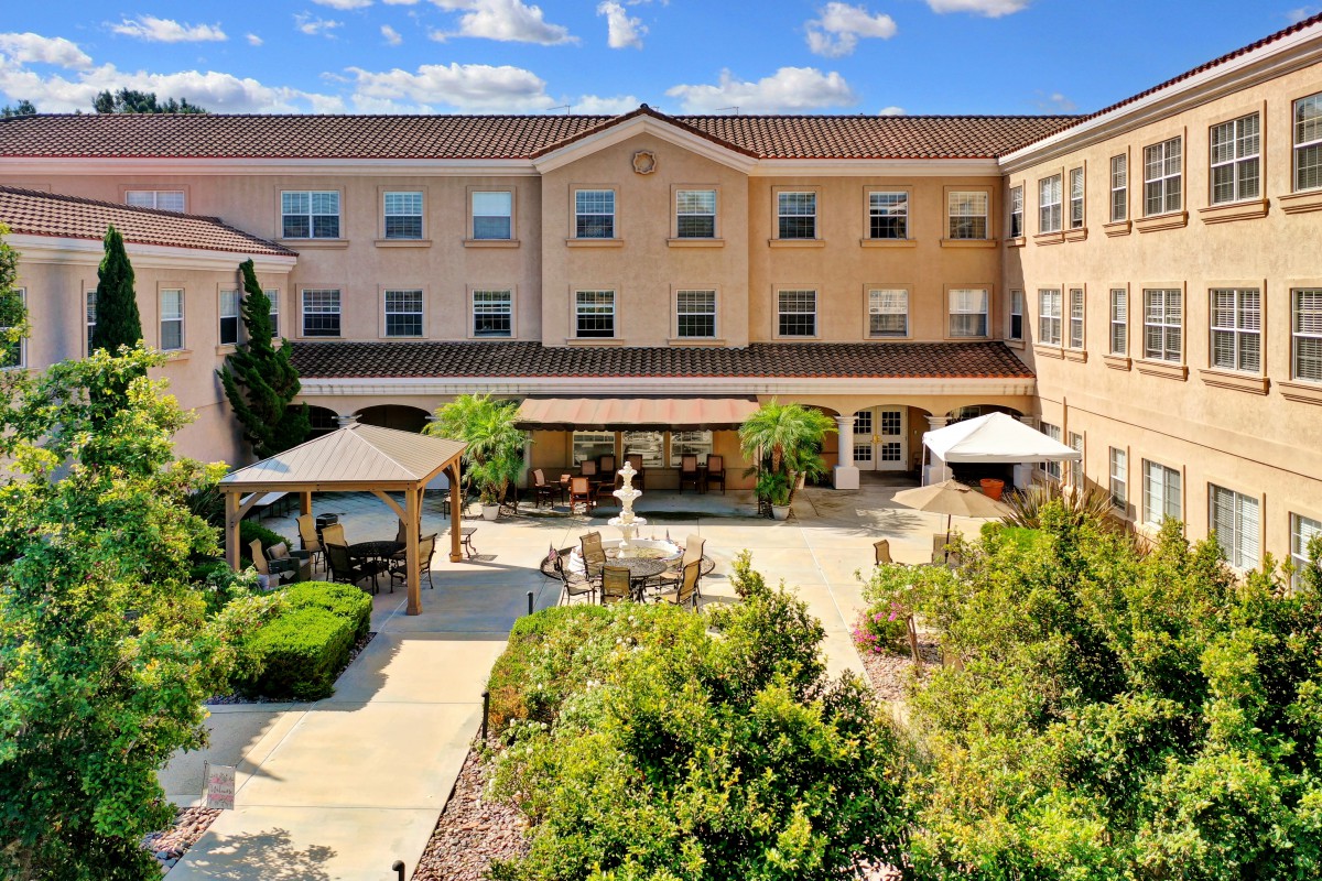 A beautifully landscaped courtyard with a fountain, surrounded by a multi-story building.