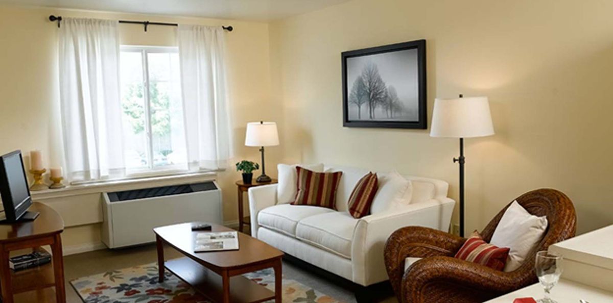 A cozy living room with a white sofa, framed artwork, and a coffee table.