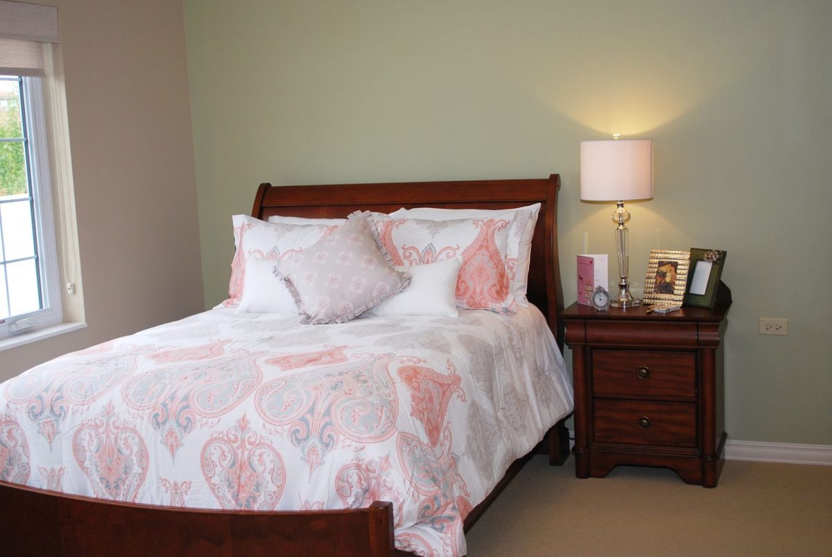A cozy, well-appointed bedroom with a wooden bed, floral bedding, and a nightstand with a lamp.